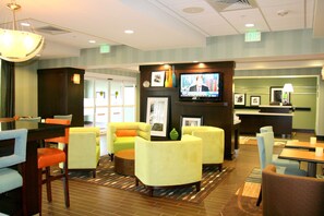 A hotel lobby with seating areas, a television, and a reception desk.