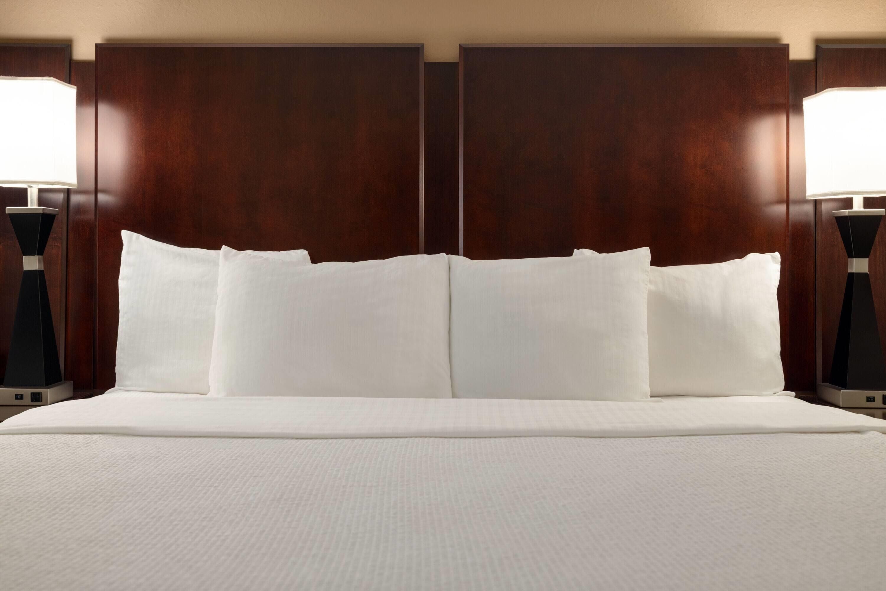A large bed with white linens and a wooden headboard.