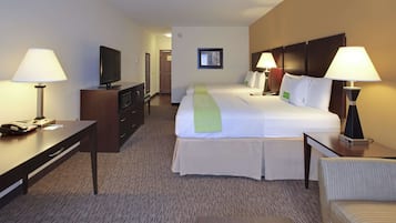 Ein Hotelzimmer mit einem großen Bett, zwei Nachttischen mit Lampen, einem Schreibtisch mit Telefon und Fernseher sowie einer Kommode.