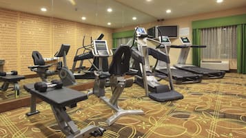 A gym with treadmills, elliptical machines, and weight benches.