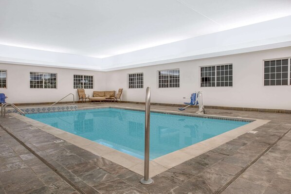 Una piscina coperta rettangolare con pavimento piastrellato e scala in metallo. Presenti quattro finestre con vetrate a griglia sulle pareti.