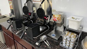 Una máquina para hacer gofres con instrucciones, una máquina para gofres, un dispensador de jarabe y una caja registradora.