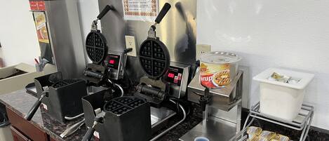 Una máquina para hacer gofres con instrucciones, una máquina para gofres, un dispensador de jarabe y una caja registradora.