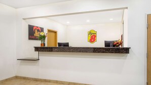 Un área de recepción con mostrador, un cartel en la pared y una puerta.
