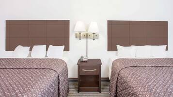 A hotel room with two beds, a nightstand with a lamp, and a telephone.