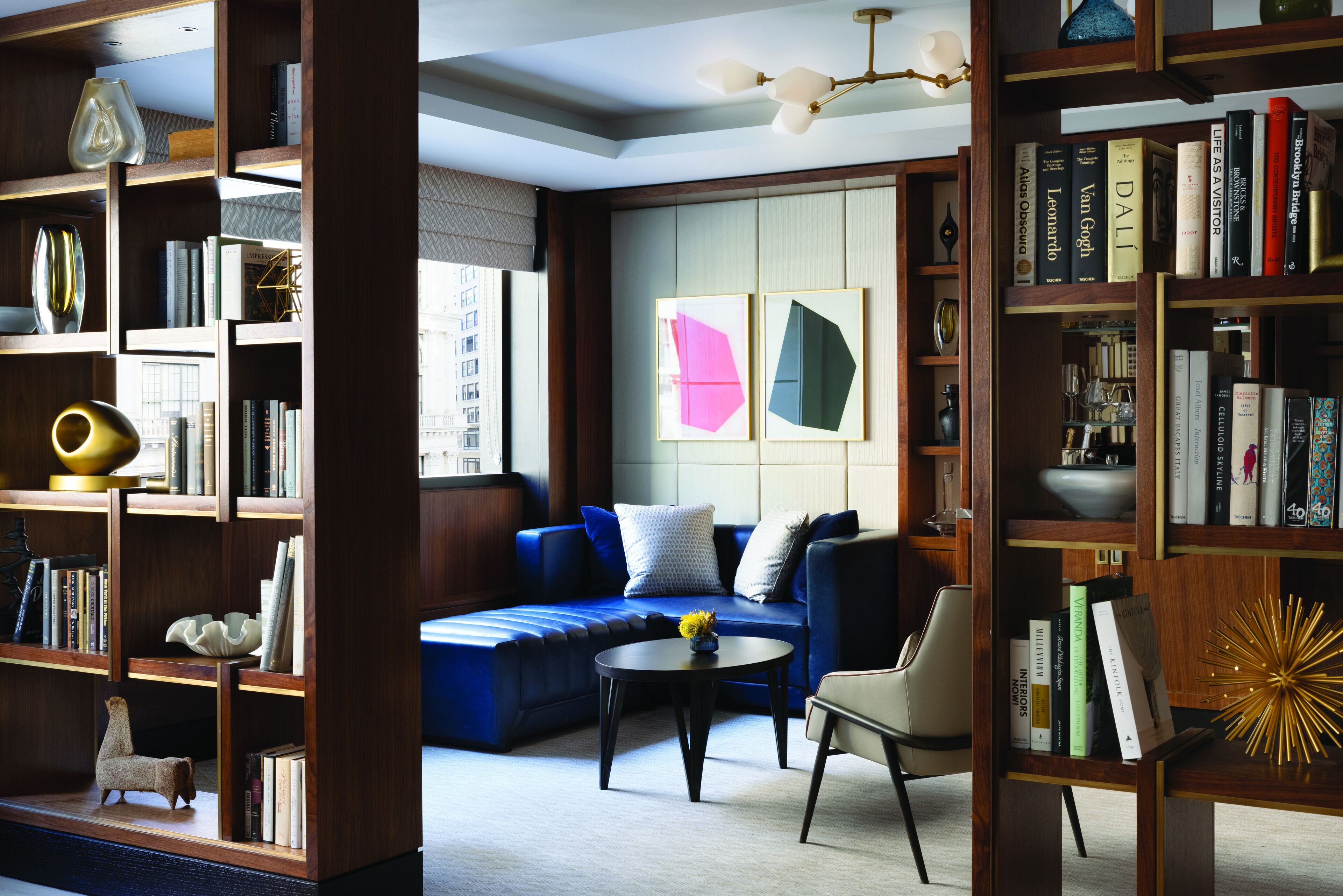 A modern living room with a blue sofa, a coffee table, and a bookshelf filled with books.