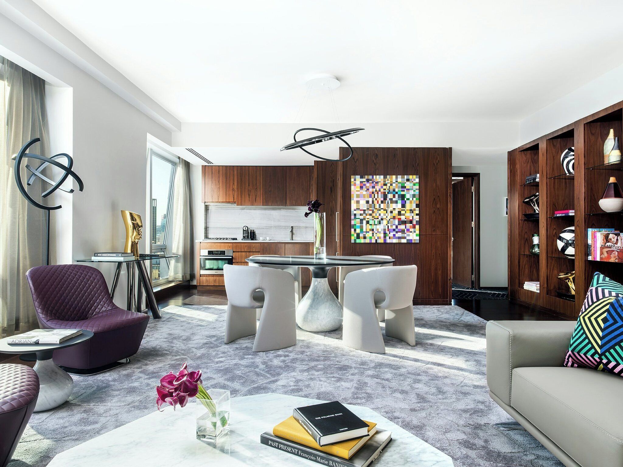 A modern living room with a dining area, a kitchen, and a view of the city.