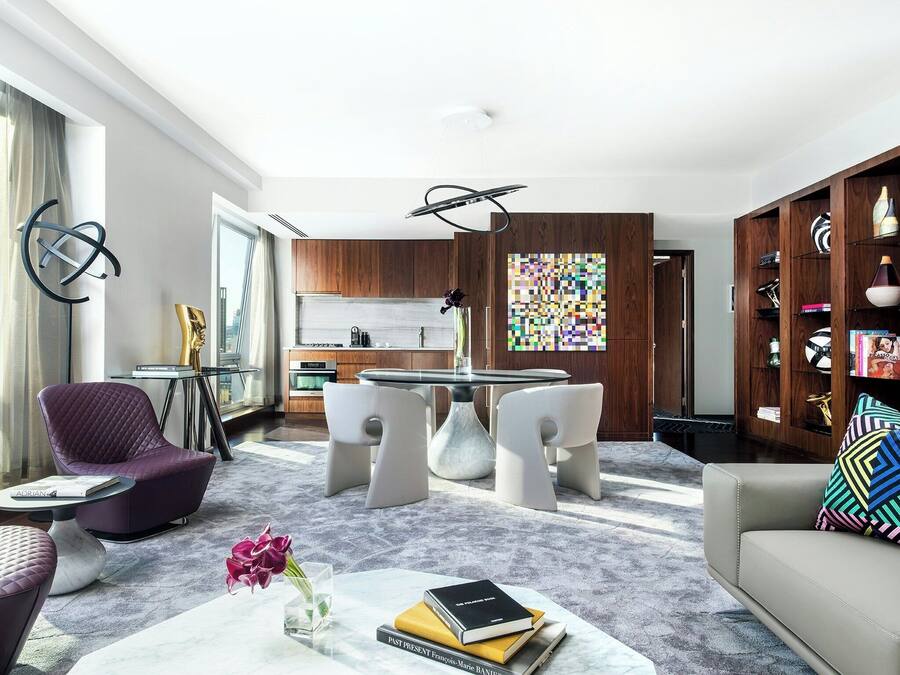 A modern living room with a dining area, a kitchen, and a view of the city.