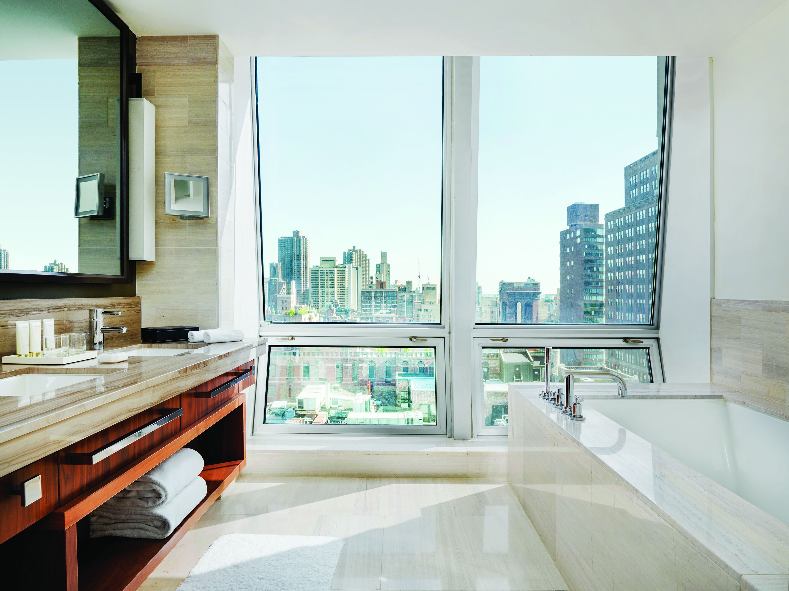 A modern bathroom with a large window, a bathtub, and a vanity with a mirror.