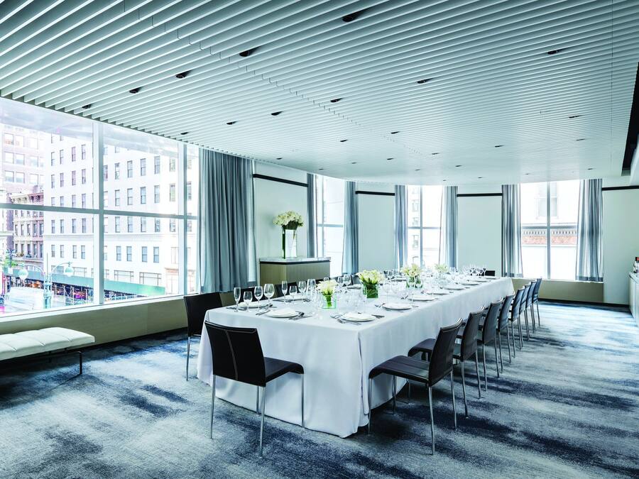 Una sala conferenze con un lungo tavolo apparecchiato per una riunione, ampie finestre e vista sulla città.