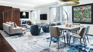 Una sala de estar moderna con un sofá, sillas, una mesa de comedor y un ventanal con vistas a la ciudad.