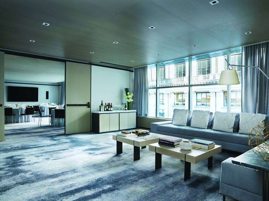 A modern living room with a sofa, coffee table, and a dining area with a TV.