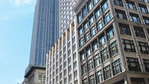 Un edificio alto con una aguja, junto a otro edificio más bajo con detalles ornamentales.