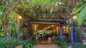 Un jardin d’intérieur agrémenté d’une pergola en bois, de tables, de chaises et de plantes en pot.