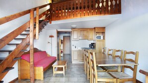 Una cocina acogedora con armarios de madera, una mesa de comedor y una escalera.
