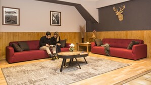 Una sala de estar moderna con dos sofás rojos, una mesa de centro de madera y una cabeza de ciervo montada en la pared.