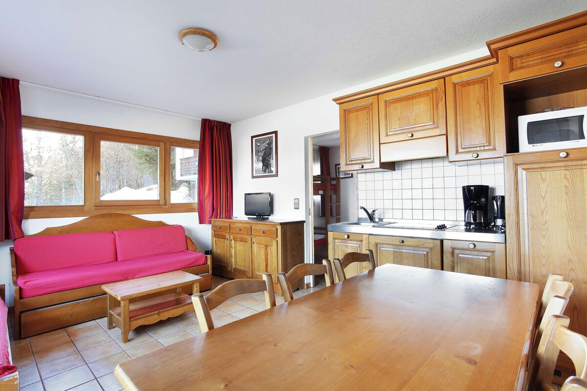 Una cocina acogedora con armarios de madera, una mesa de comedor y un sofá rojo.