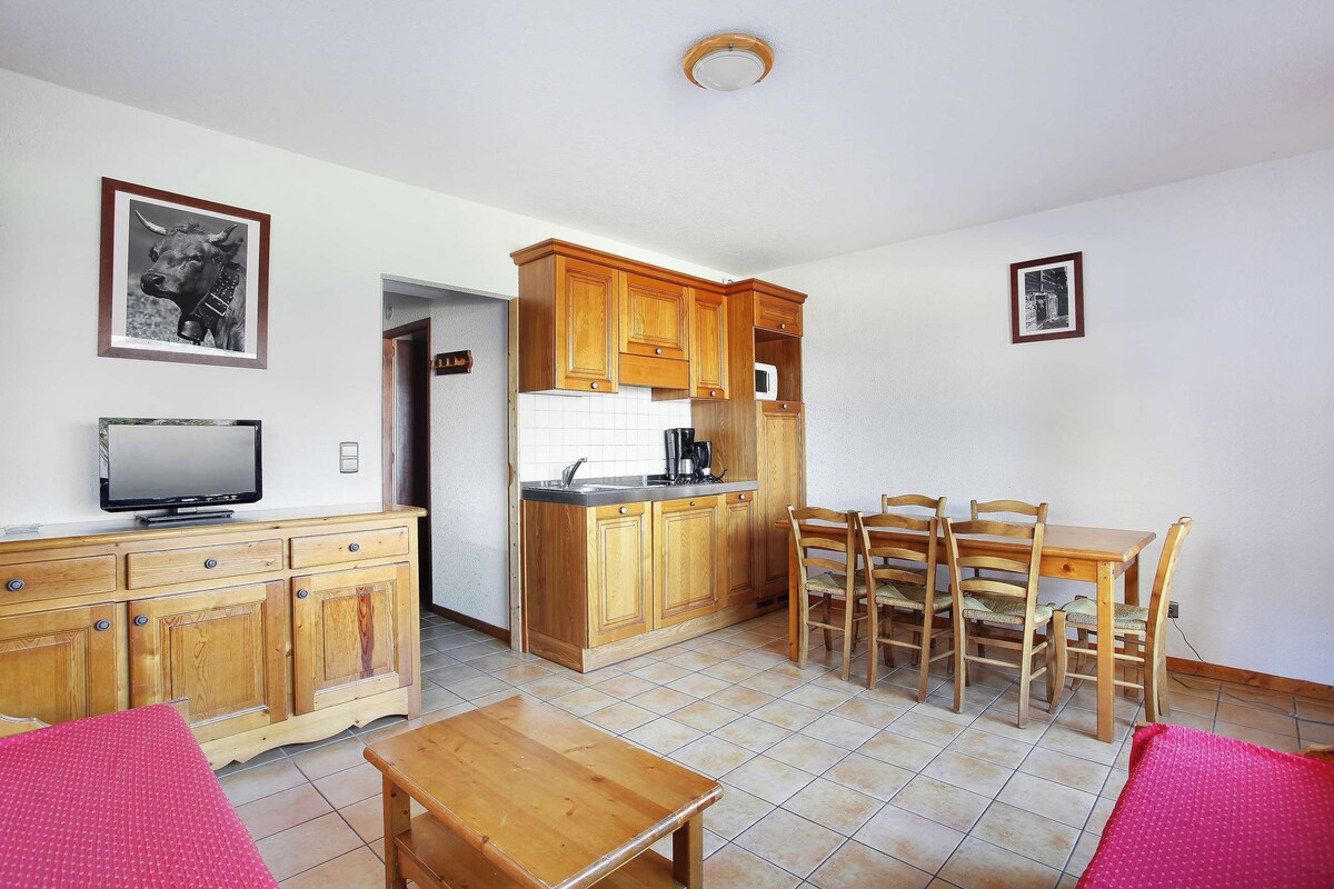 Un espacio habitable compacto con kitchenette, muebles de madera y televisor.