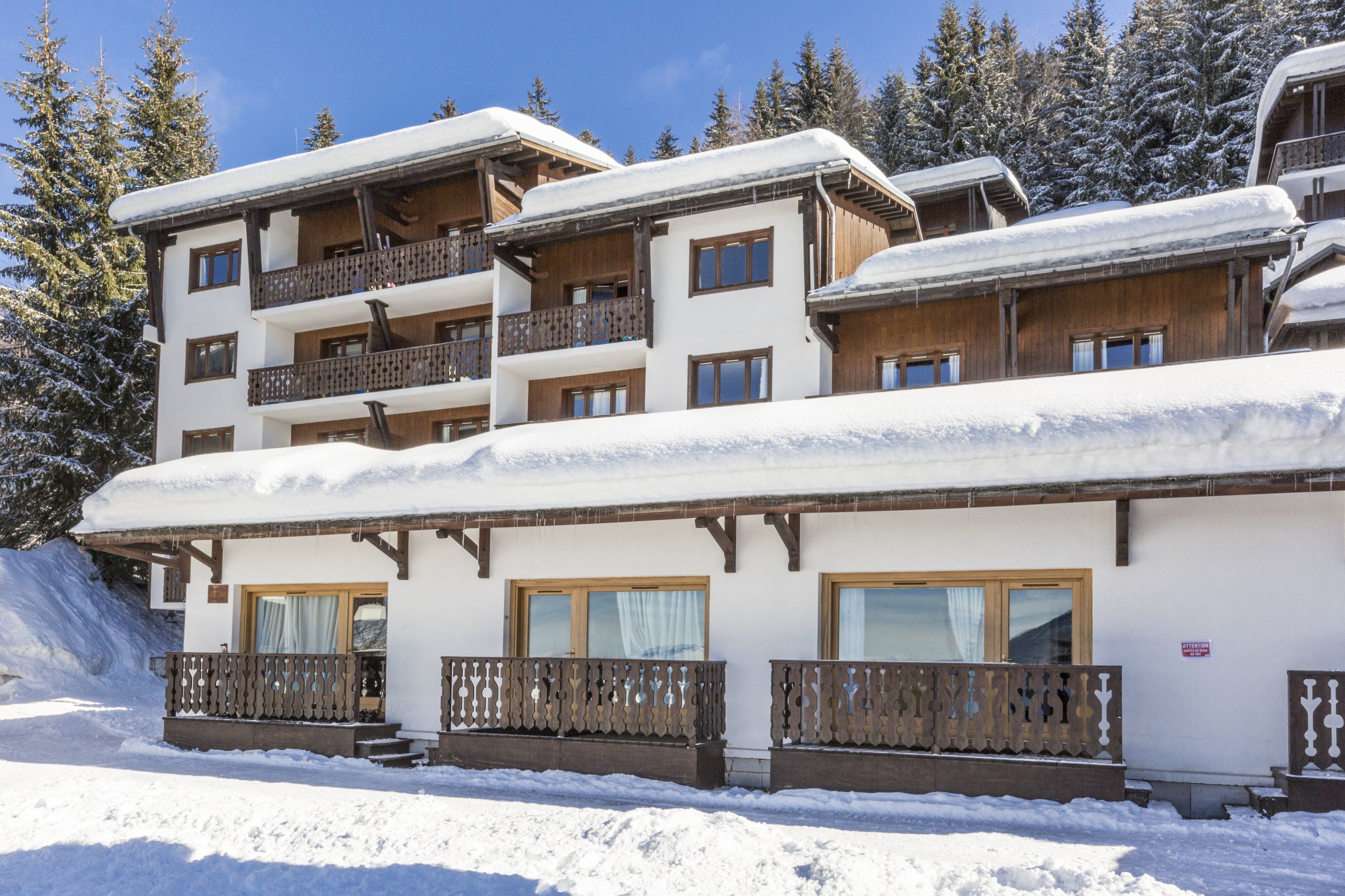 A multi-story hotel with wooden balconies and snow-covered roofs.
