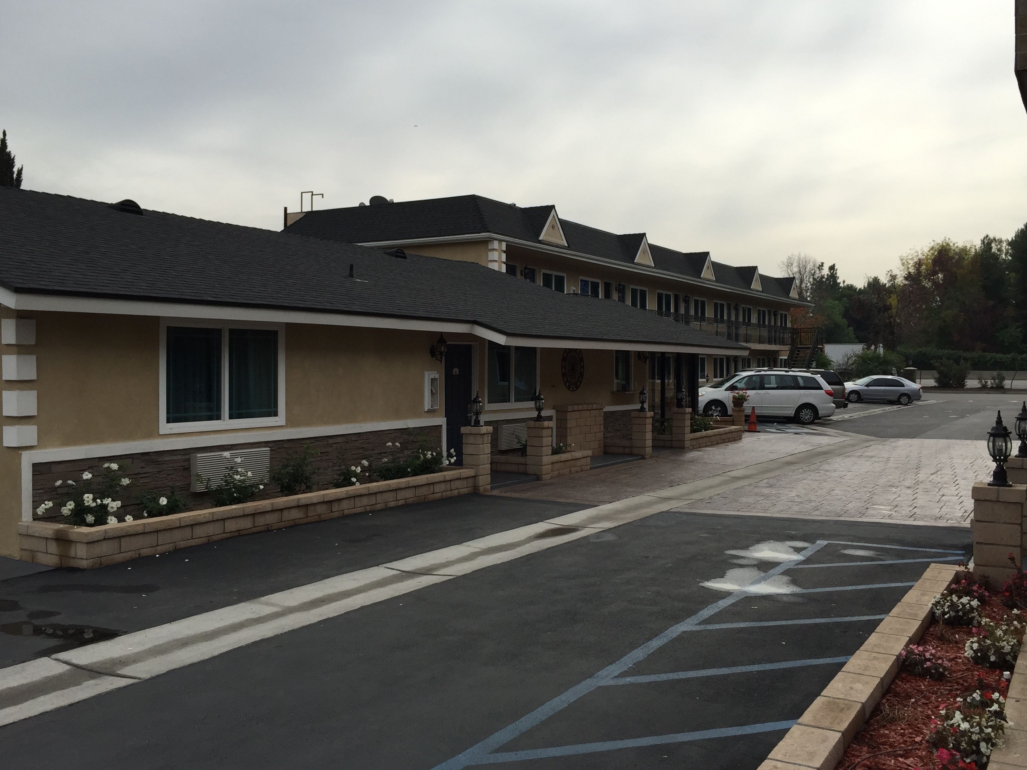 A row of motel-style buildings with a parking lot in front.