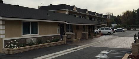 A row of motel-style buildings with a parking lot in front.
