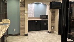 A modern kitchen with dark cabinets, a granite countertop, and a built-in microwave. - Walnut Inn & Suites West Covina (West Covina)