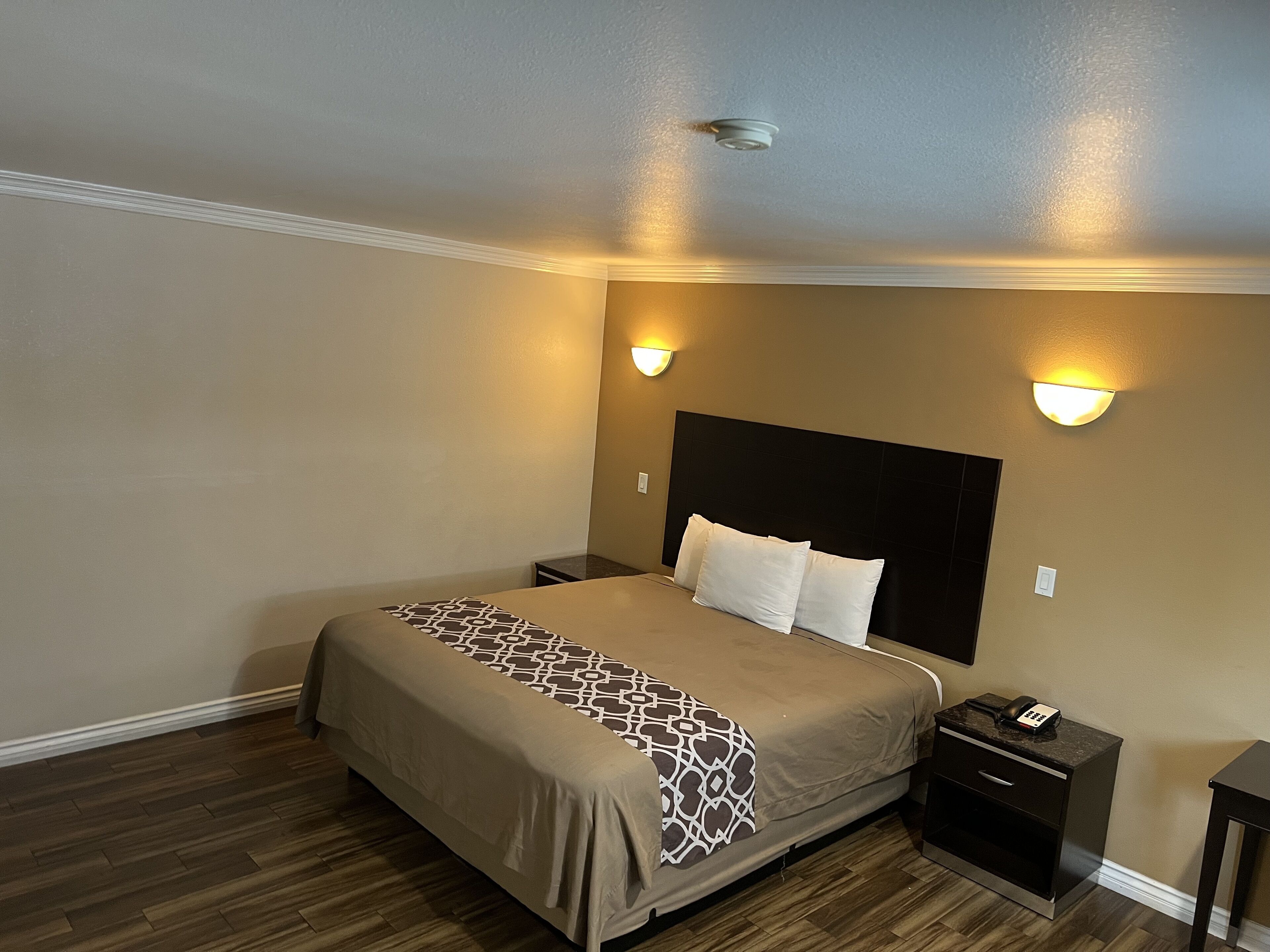 Une chambre à coucher avec un grand lit, deux tables de chevet, une commode et des lampes fixées au mur.
