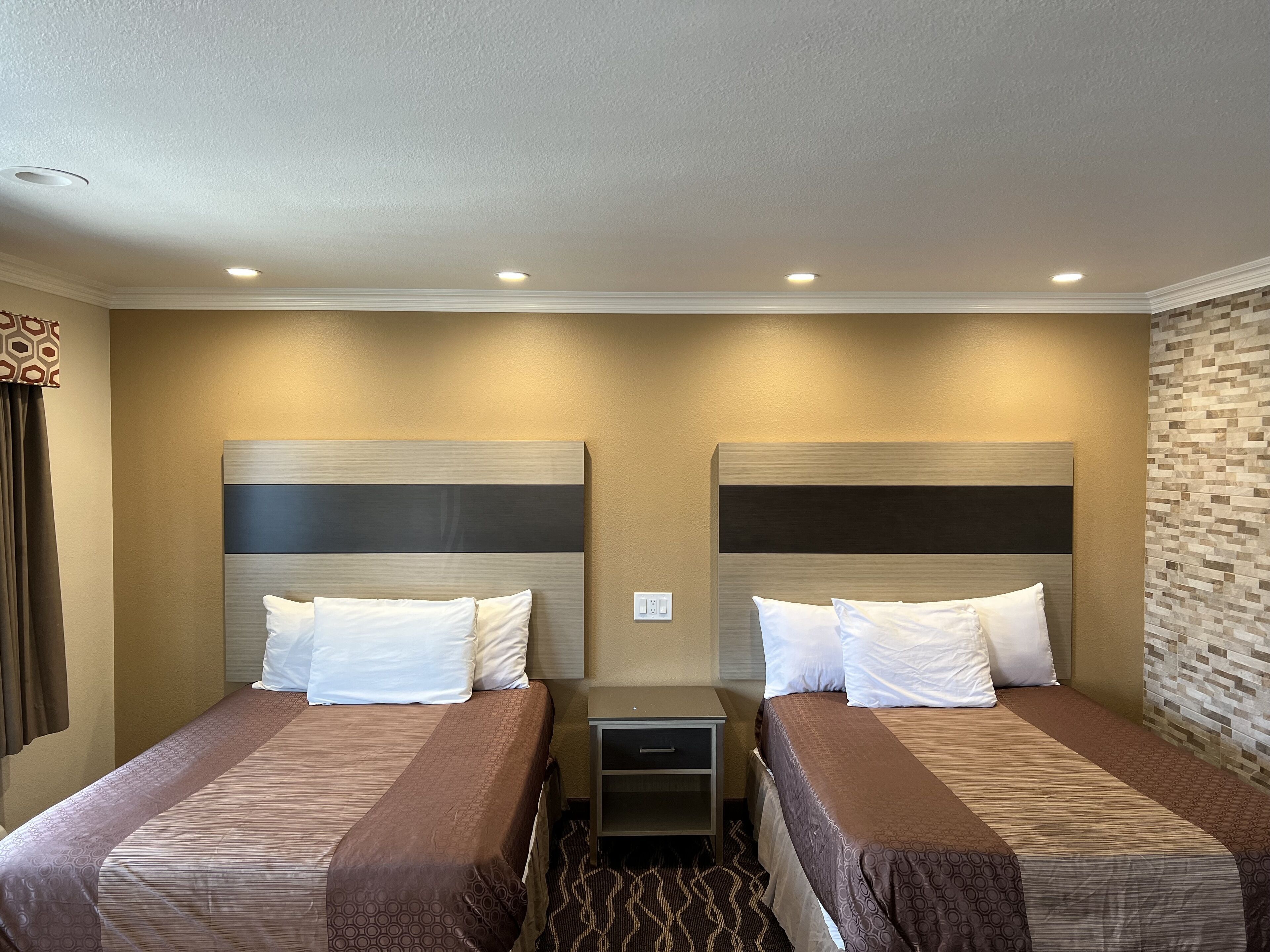 Habitación de hotel con dos camas, un escritorio pequeño y una mesita de noche.