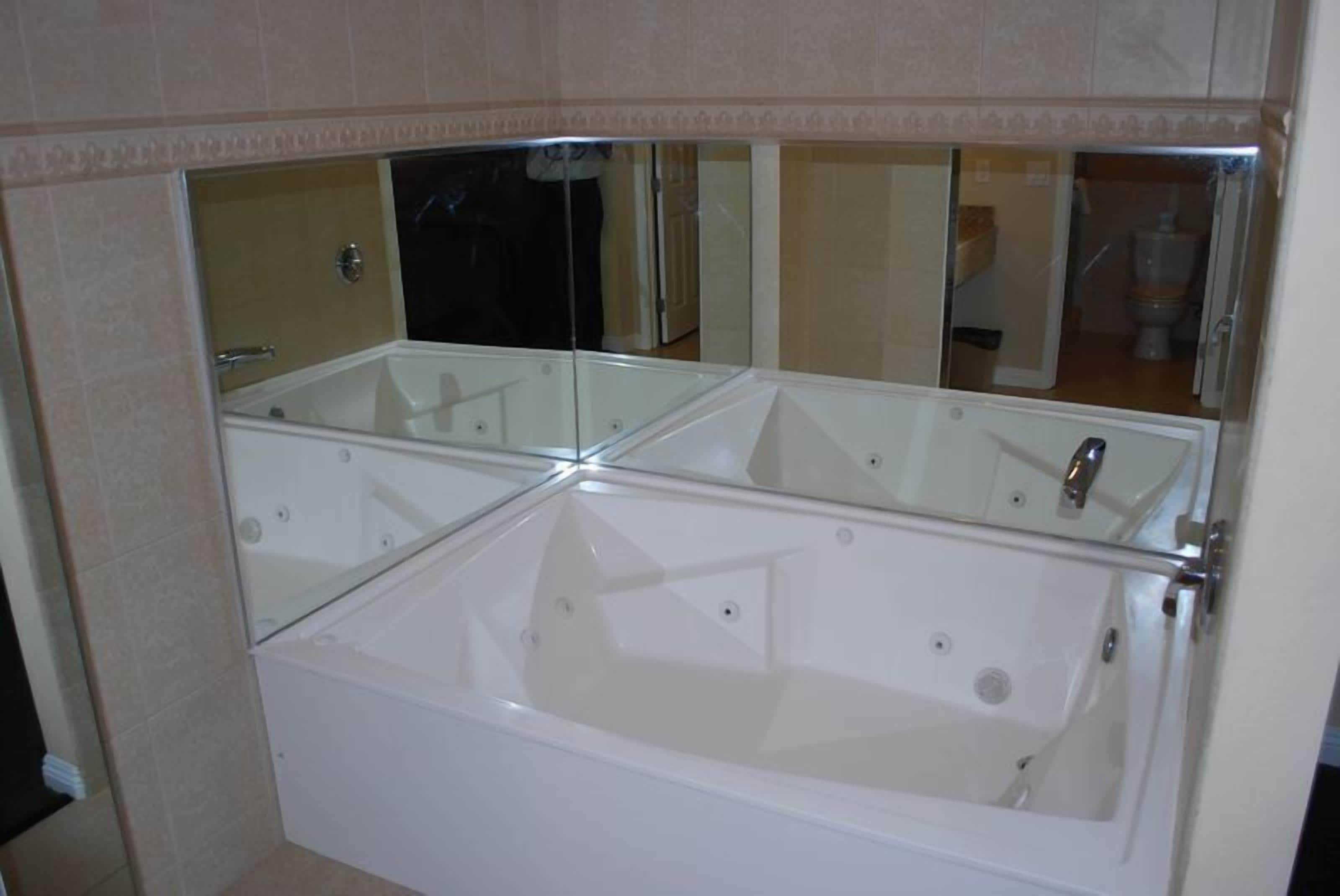 A bathroom with a large bathtub, a glass-enclosed shower, and a mirror above the tub.