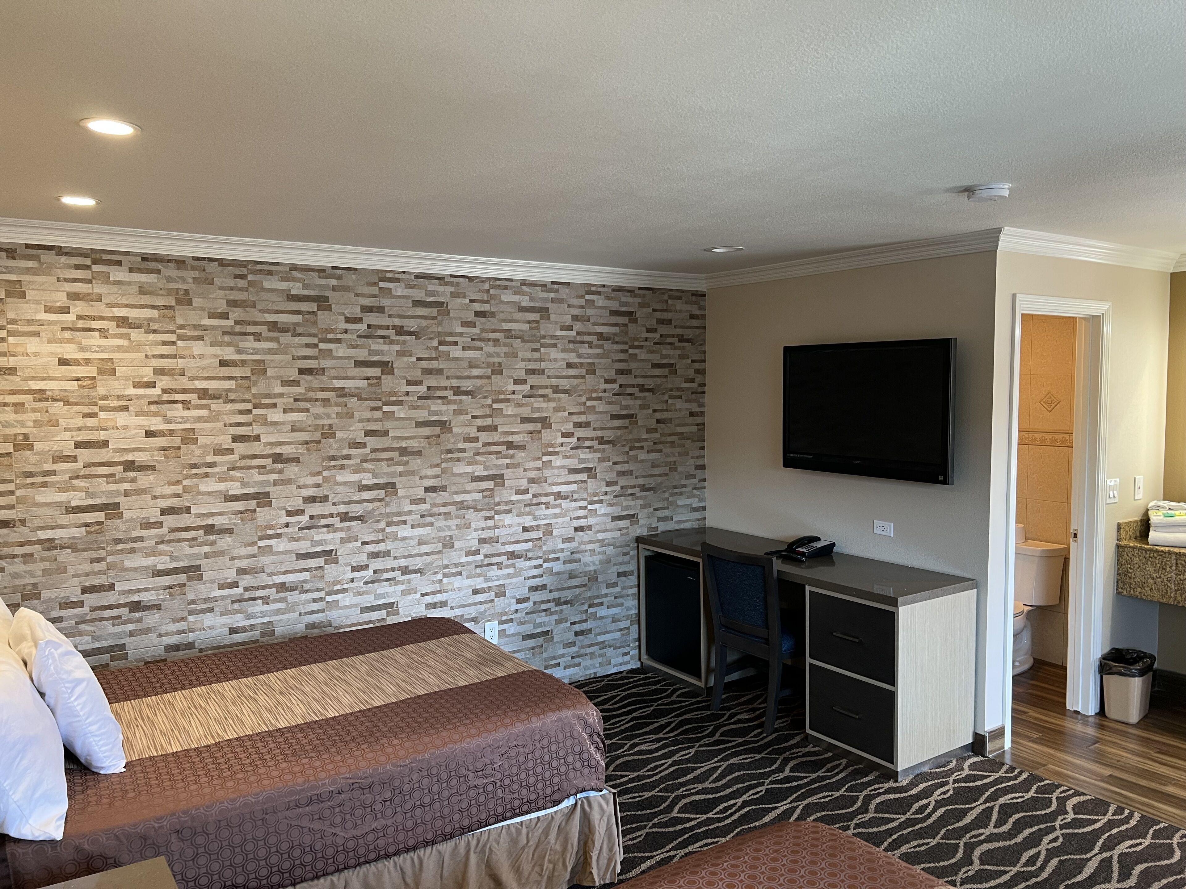 A hotel room with a bed, desk, and television.