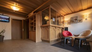 Eine Hotelhalle mit Holzwandverkleidung, einem Fernseher, einem roten Sessel und einer Sitzecke mit Tisch und Stühlen.