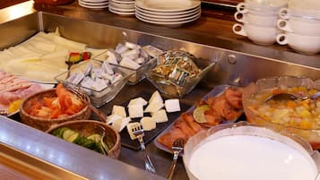 Ein Buffet mit verschiedenen Speisen, darunter Fleisch, Käse und Obst.