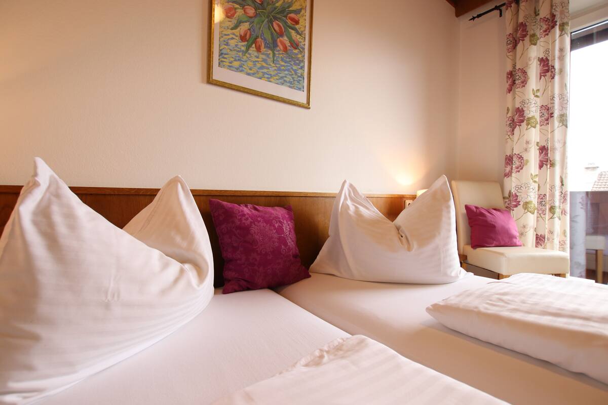 Habitació d'hotel amb dos llits, roba de llit blanca i un panell de capçal de fusta.
