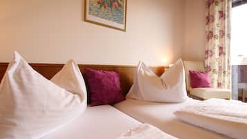 Ein Hotelzimmer mit zwei Betten, weißer Bettwäsche und einem hölzernen Kopfteil.
