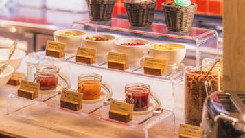 Een buffet met diverse gerechten en toevoegingen, waaronder potten jam en manden met brood.
