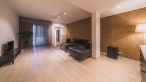 Ein modernes Wohnzimmer mit einer Couch, einem Fernseher, einer Lampe und einer Wand mit Muster.