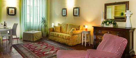A living room with a sofa, armchair, and a dining area with a table and chairs.
