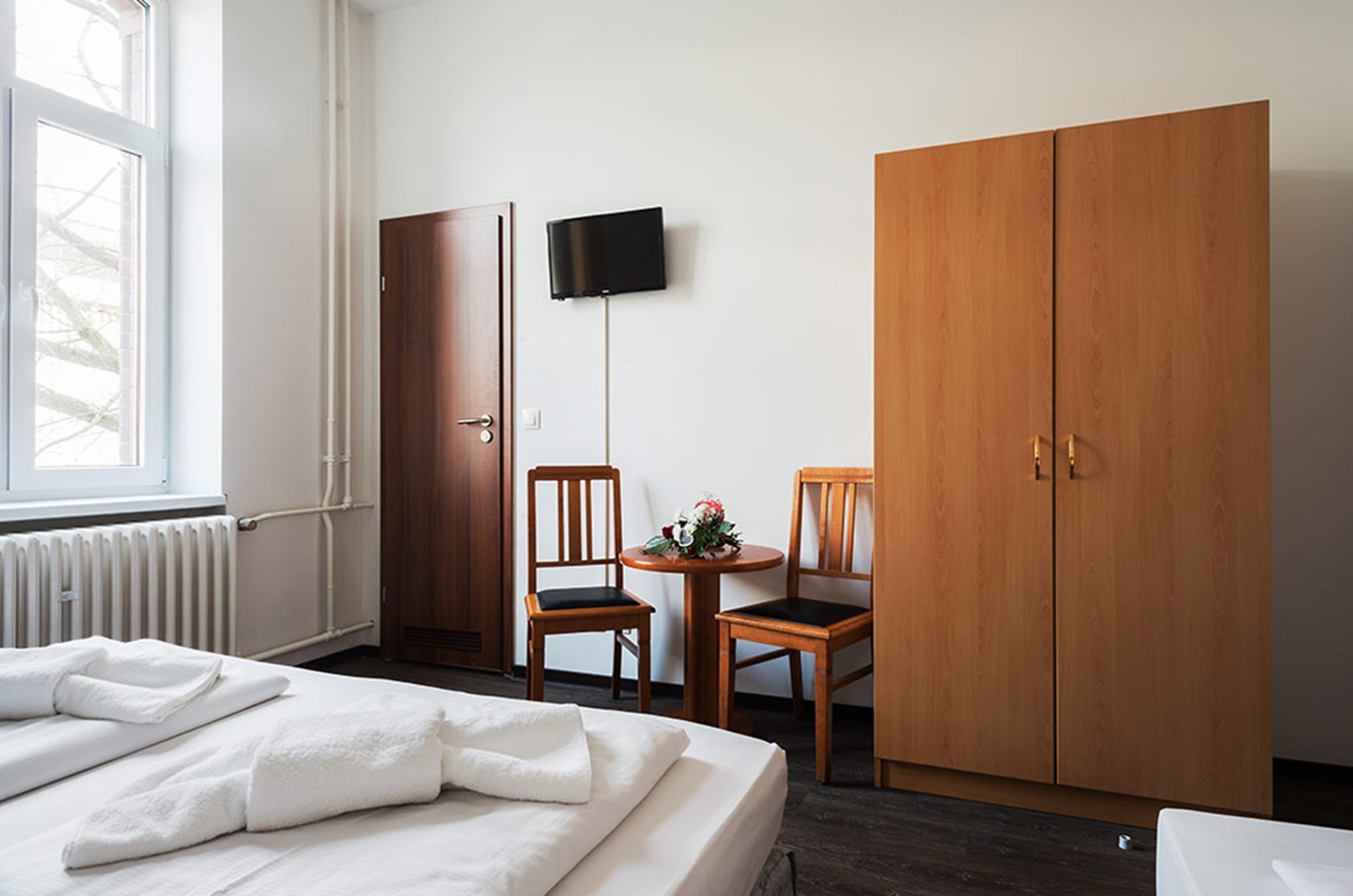 Habitació d'hotel amb un llit, un armari, una televisió i dues cadires.