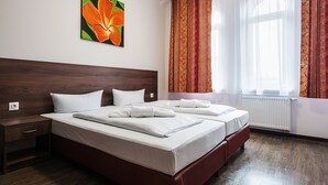 A hotel room with a large bed, a nightstand, a painting of a flower, and a window with curtains. - Hotel Queenspark (Berlin)