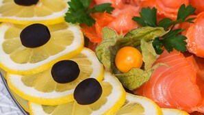 A platter of sliced lemons, black olives, cherry tomatoes, parsley, and salmon. - Hotel Queenspark (Berlin)