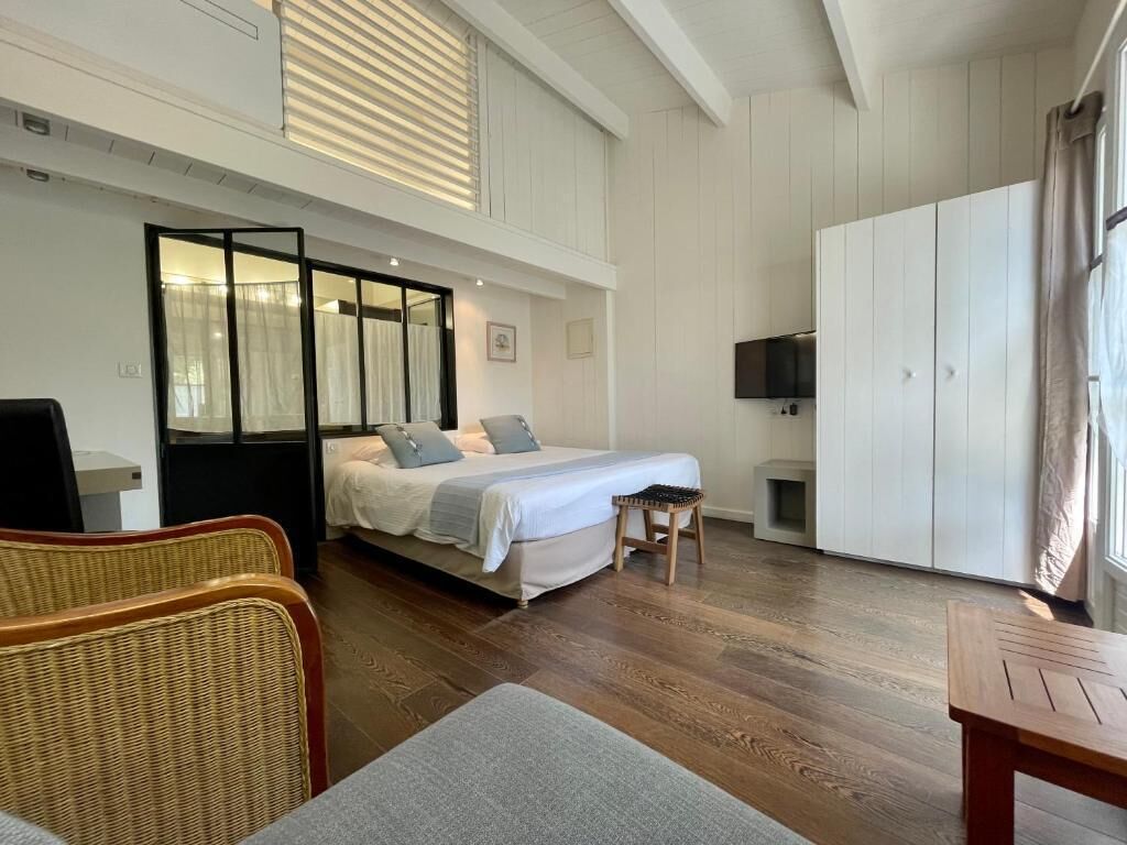 Une chambre d’hôtel comprenant un lit, une télévision, une armoire et un coin salon avec une chaise et une table.