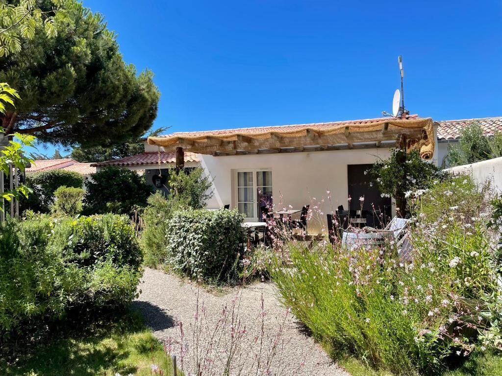A house with a tiled roof, a satellite dish, and a garden with various plants and a gravel path.