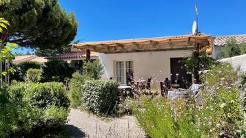 A house with a tiled roof, a satellite dish, and a garden with various plants and a gravel path.