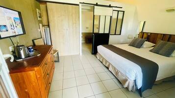 Hotelkamer met een bed, een houten dressoir, een bureau met waterkoker en een televisie aan de muur.
