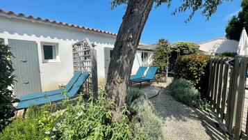 Un patio con dos sillones azules, una cerca de madera y un pequeño jardín con diversas plantas.