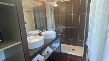 Un baño moderno con dos lavamanos, un espejo grande y una zona de ducha.
