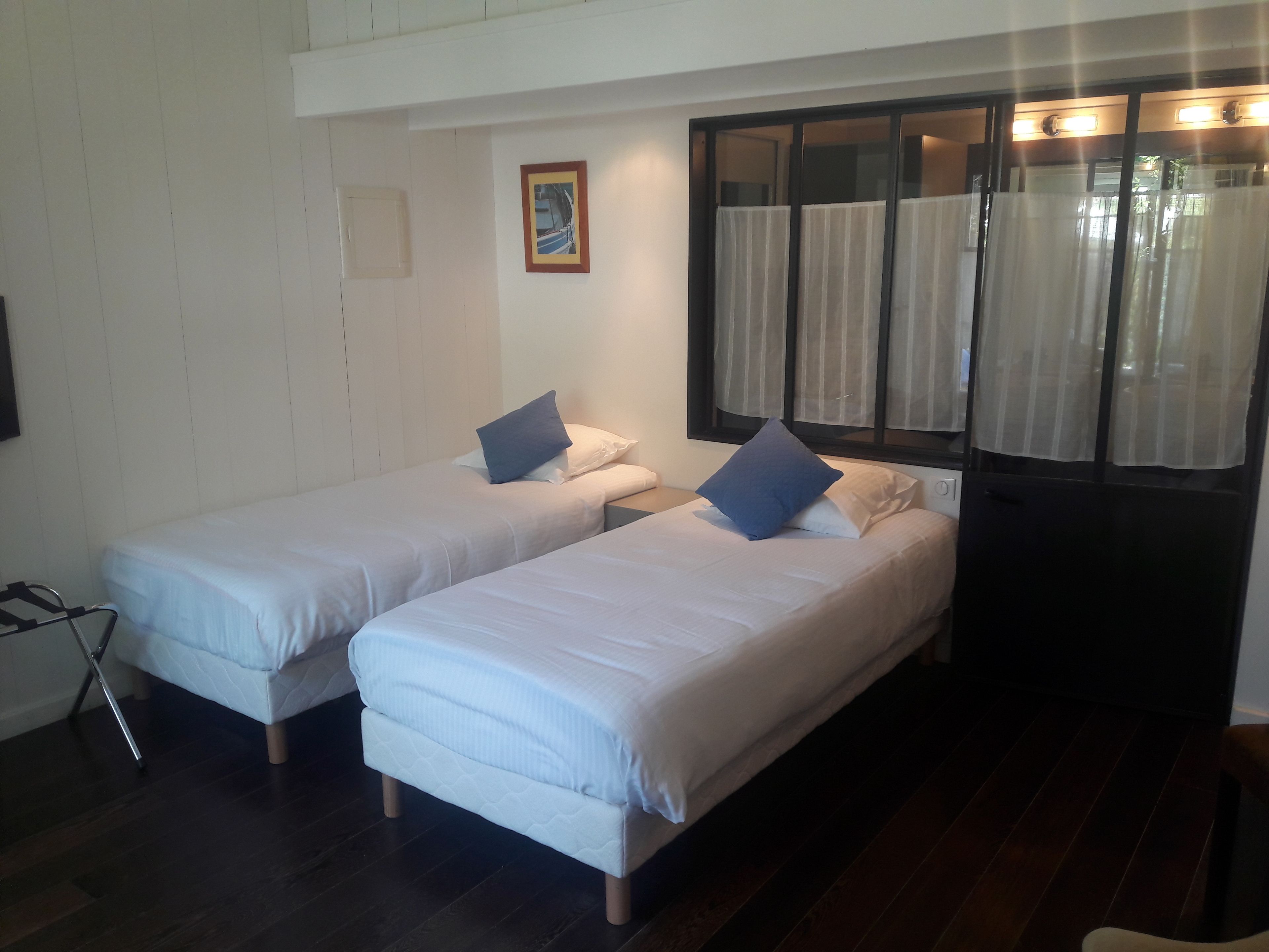 A room with two single beds, a small table, and a window with curtains.