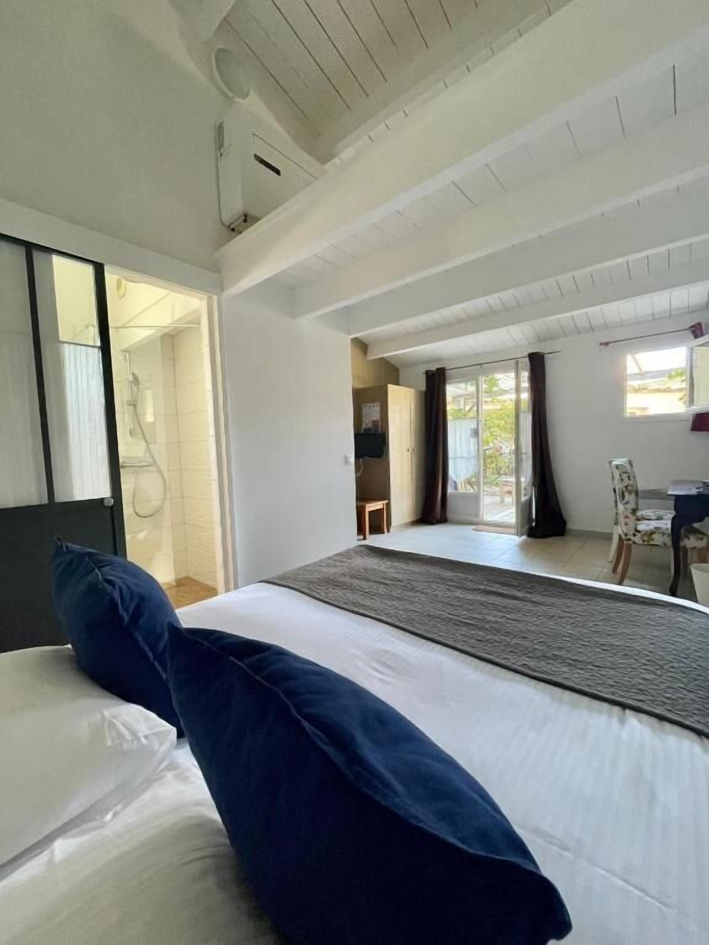 A hotel room with a large bed, a view of the outdoors, and a door leading to a bathroom.