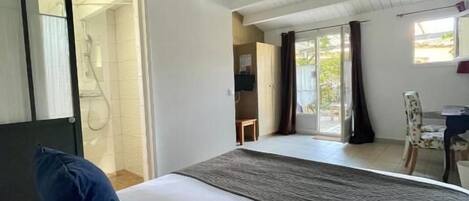 A hotel room with a large bed, a view of the outdoors, and a door leading to a bathroom.
