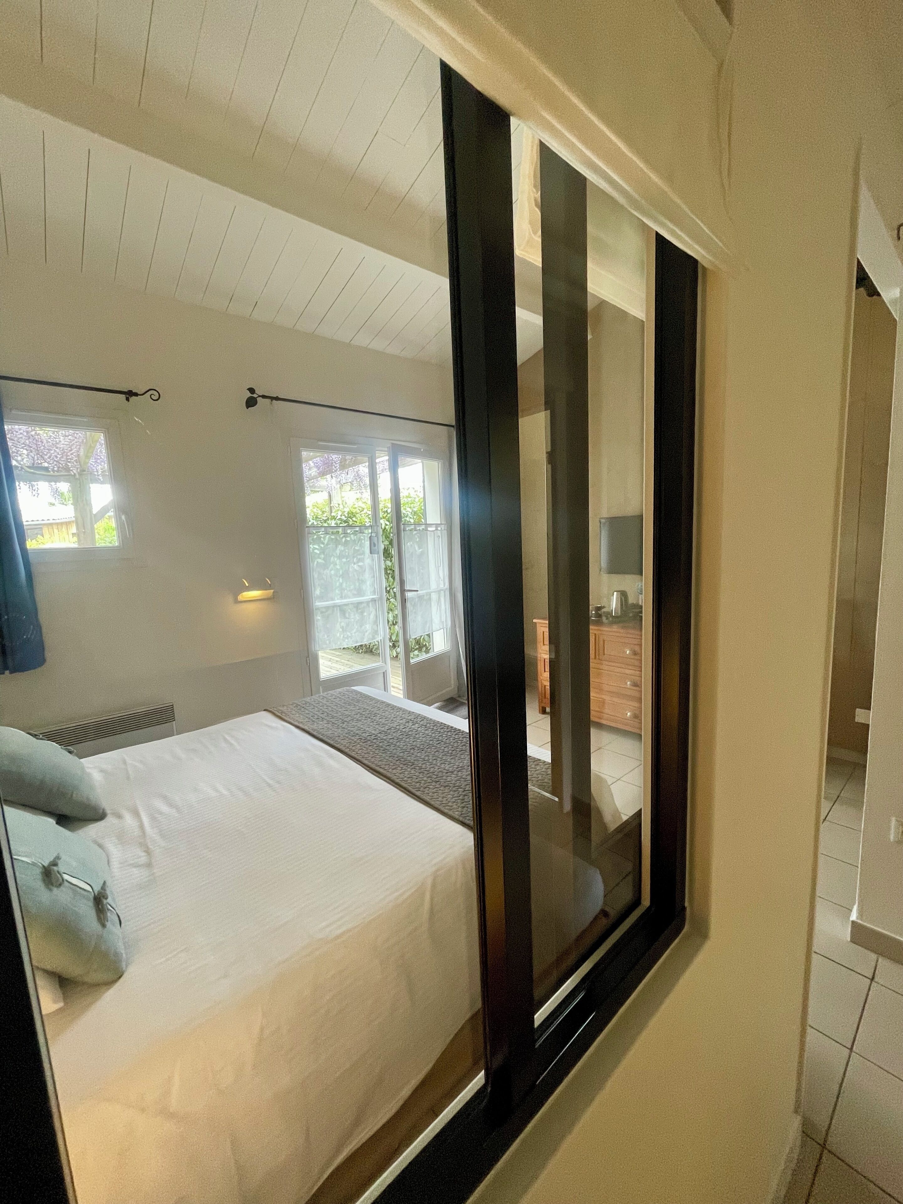 A bedroom with a large bed, a sliding glass door to a balcony, and a view of the outdoors.